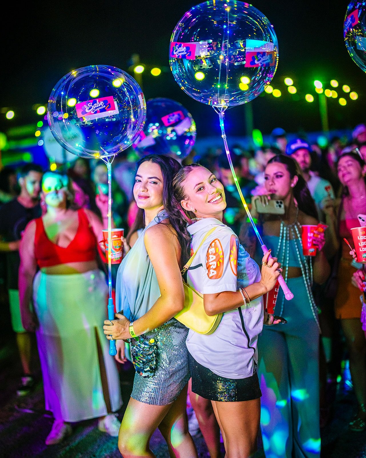 Duas participantes sorrindo com balões personalizados do Salve Simpatia
